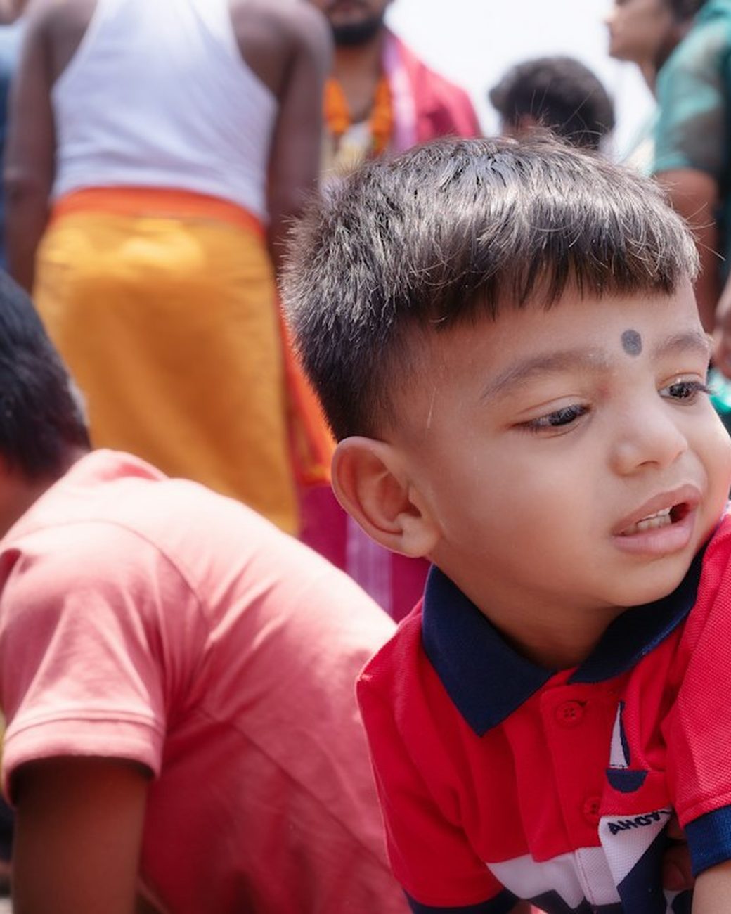 A small boy looking around in a crowd